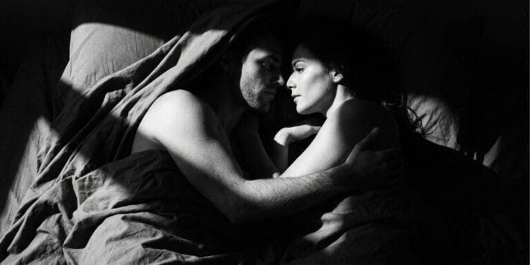 Couple sharing a quiet intimate moment in bed, illustrating essential oils for sex and intimacy