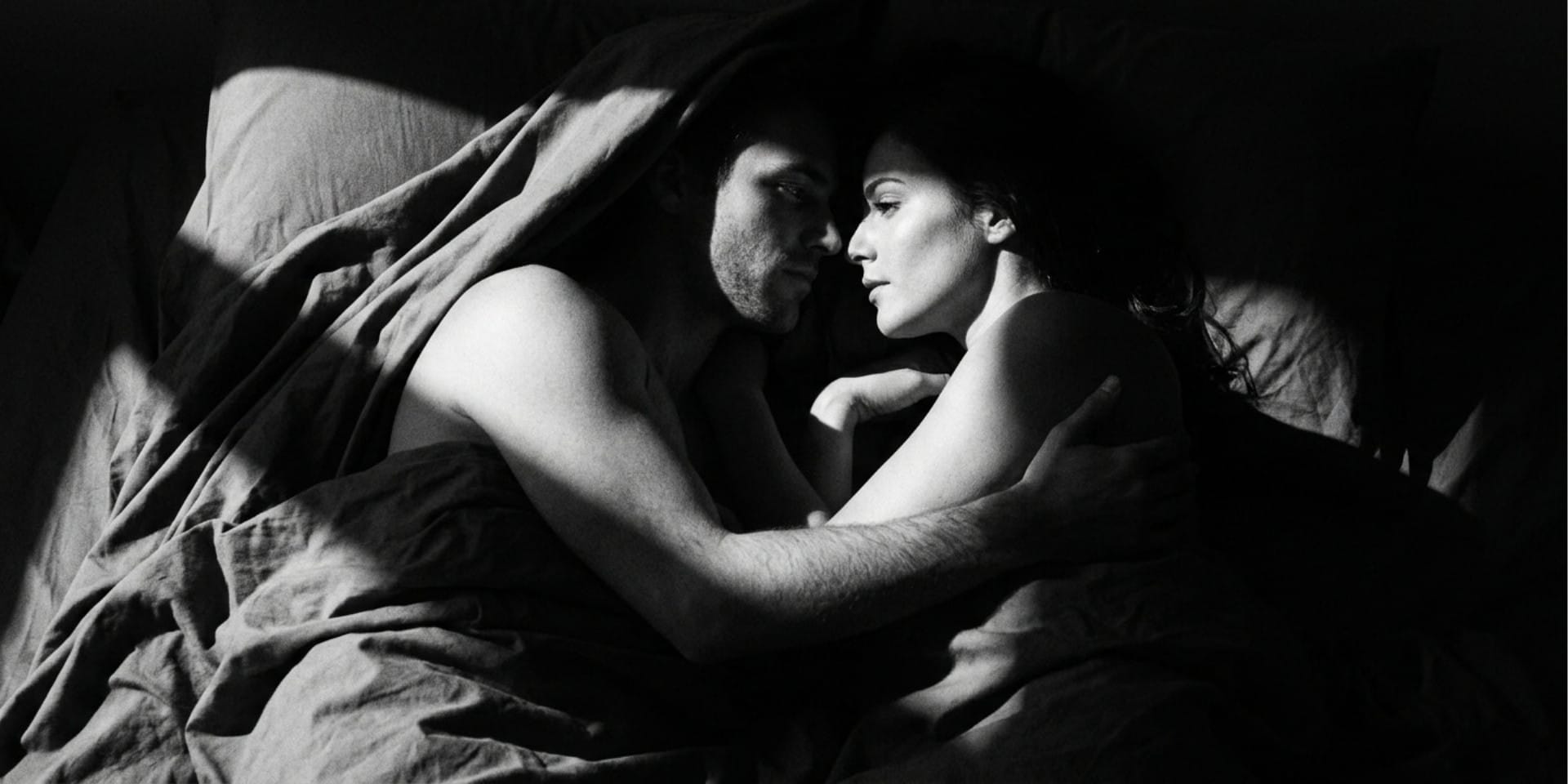 Couple sharing a quiet intimate moment in bed, illustrating essential oils for sex and intimacy