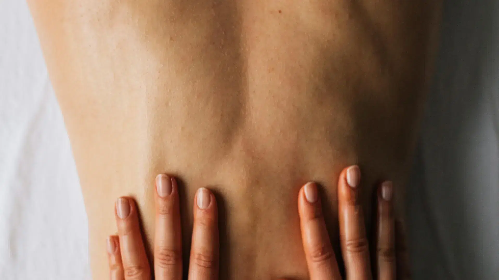 Close-up of hands massaging a person's back with sensual massage oil, creating a warm and intimate relaxation experience