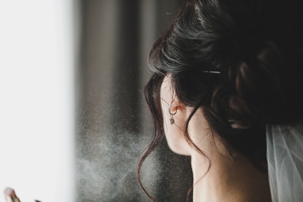 A woman spraying perfume near her neck with fragrance mist visible – what is a pheromone perfume