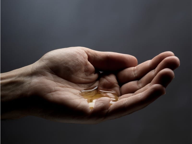 A few drops of natural body oil resting in the palm of a hand, showing the nourishing texture of Wildfire’s plant-based oils