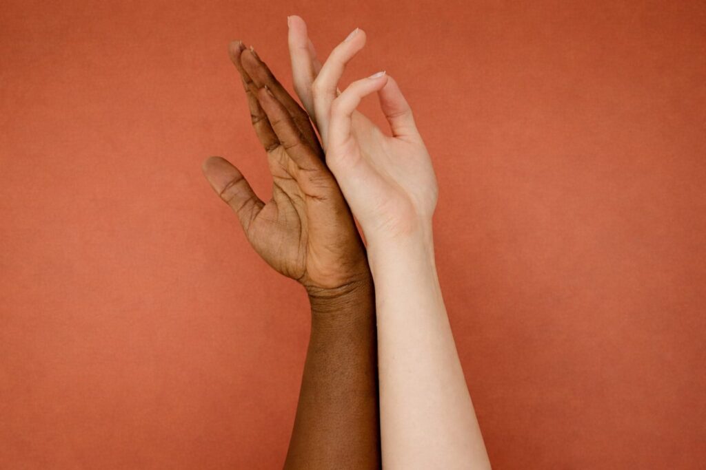 Two diverse hands touching against a warm terracotta background representing intimacy and connection