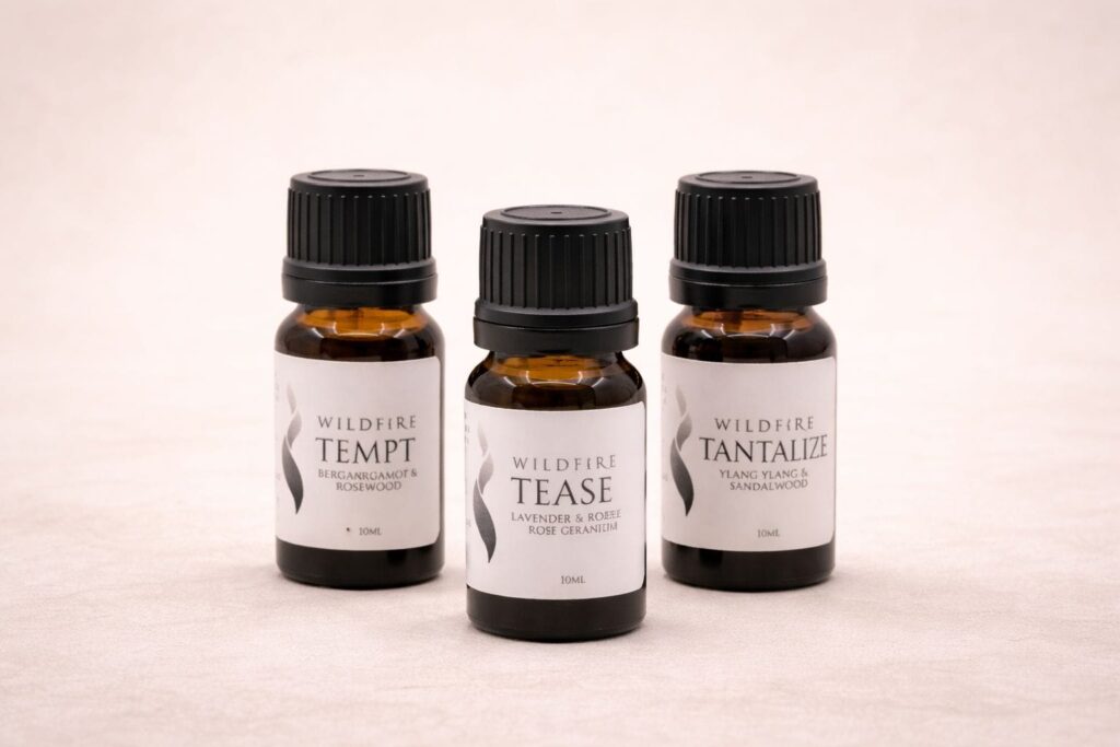 Three Wildfire aphrodisiac essential oil blends presented together as the Trilogy collection on a soft neutral background