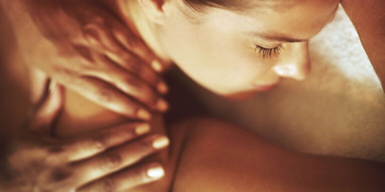 Person receiving an erotic massage with slow, intentional touch focused on presence and connection