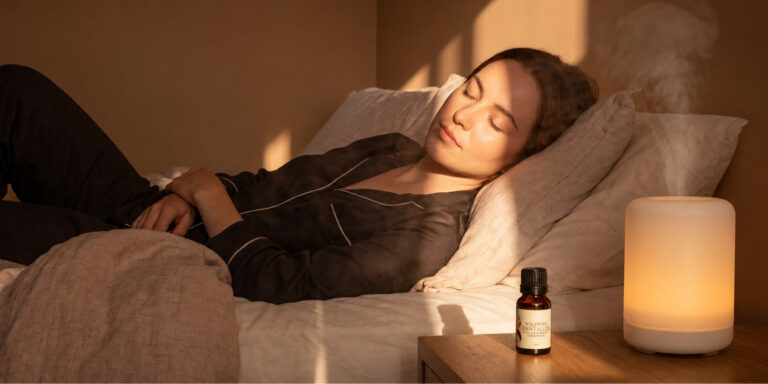 Woman relaxing beside a diffuser and Wildfire essential oil for calm and relaxation