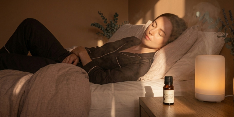 Woman relaxing beside Wildfire Tantalize oil, candle and diffuser for essential oils for mood and relaxation rituals