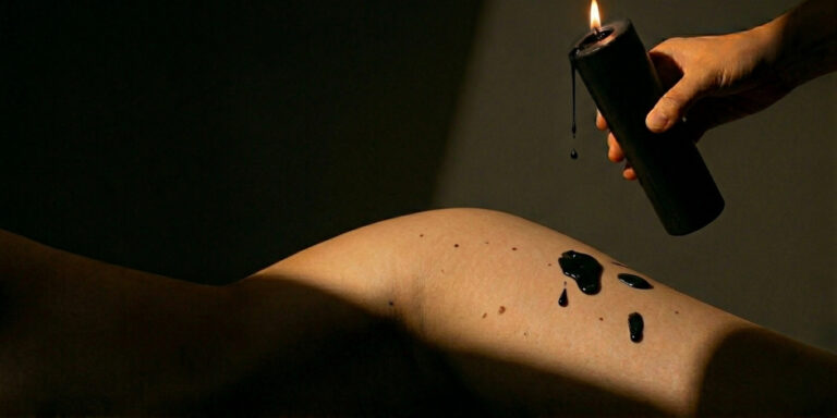 Wax play and temperature play with a black wax play candle dripping wax onto an upper thigh