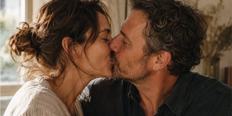 A couple sharing a quiet, mutually welcomed kiss in warm natural light.