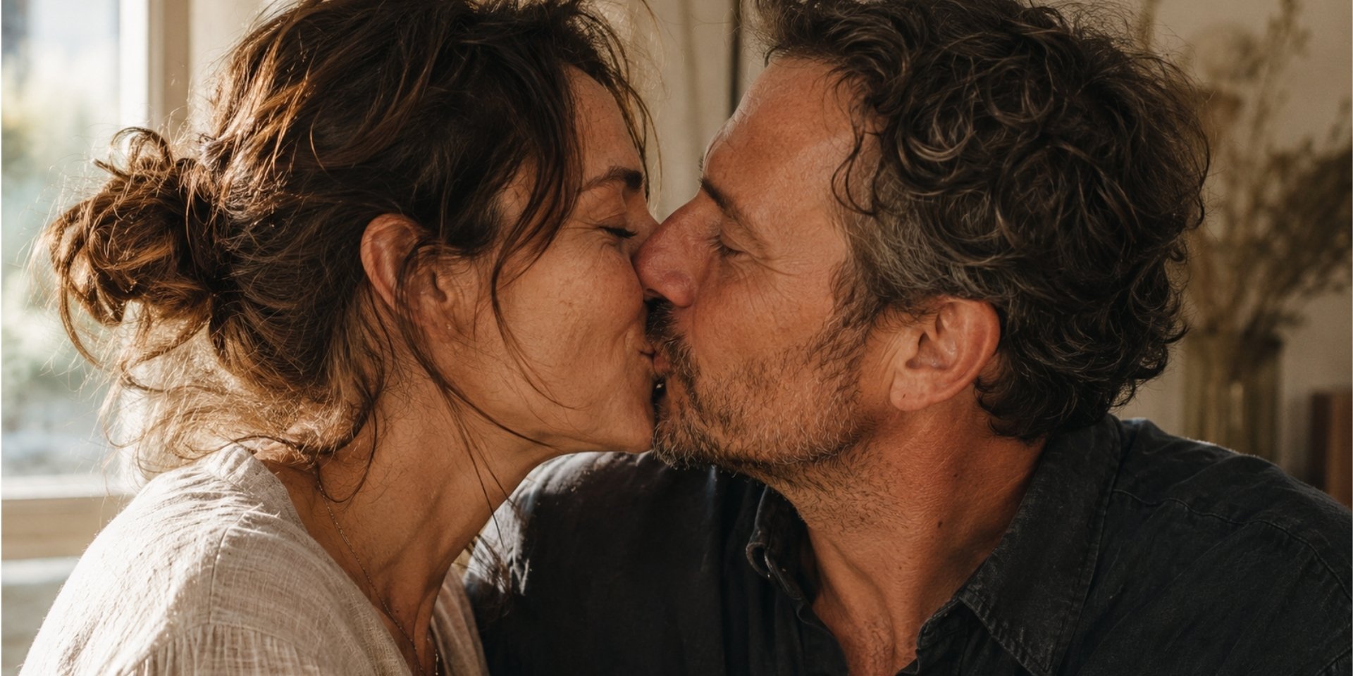 A couple sharing a quiet, mutually welcomed kiss in warm natural light.
